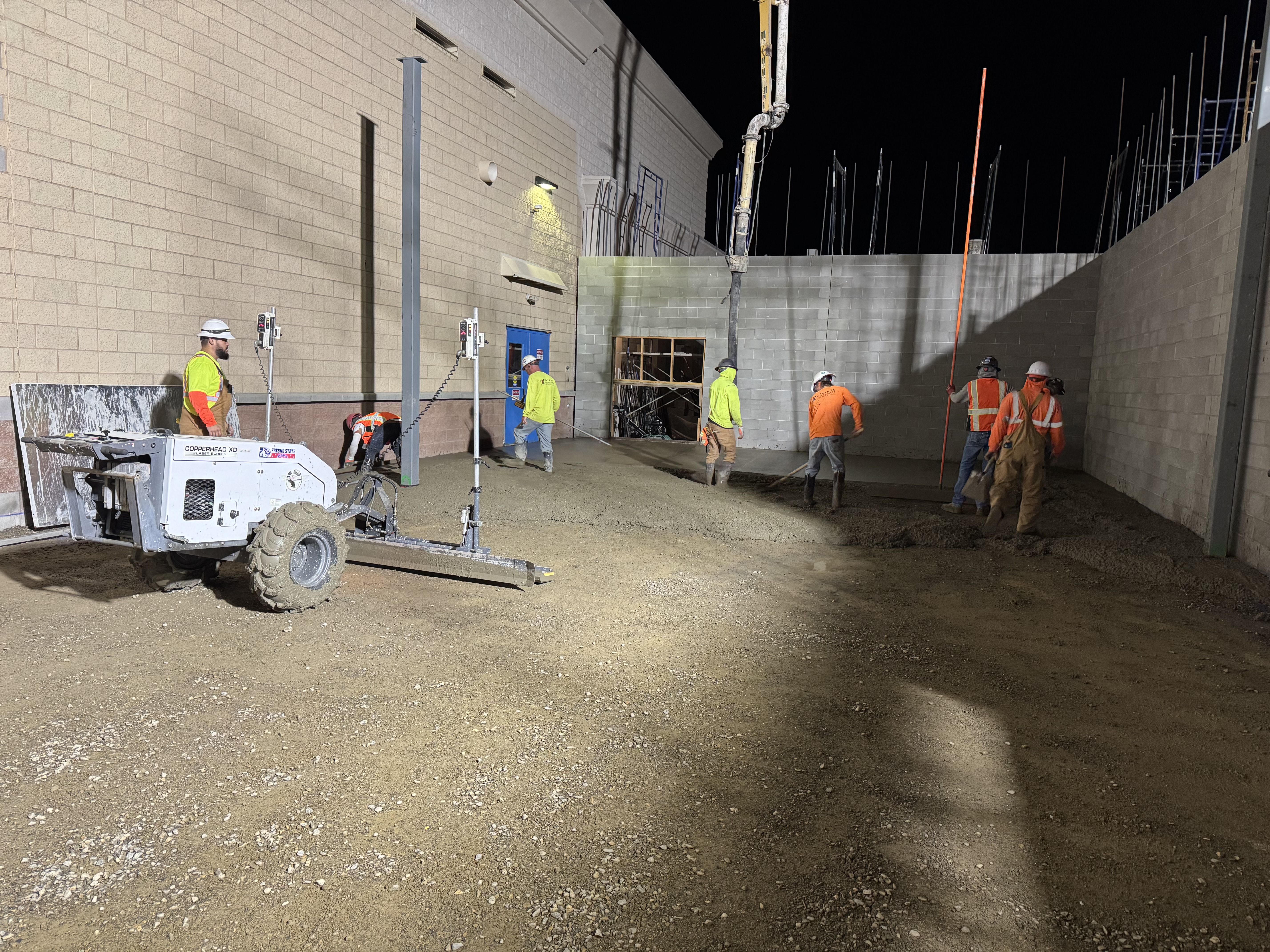 Night crew finishing concrete at commercial loading dock area on industrial project