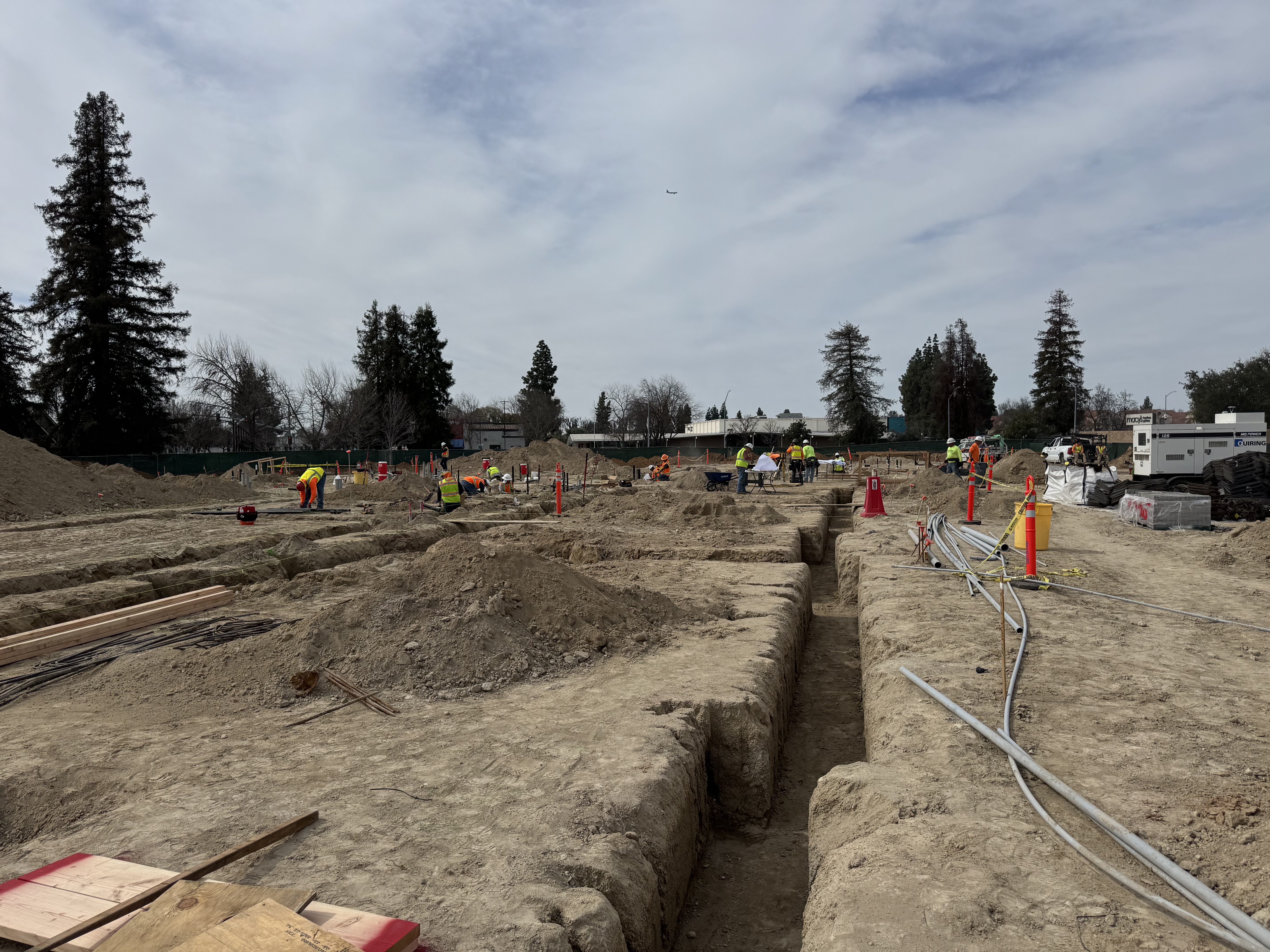 Large-scale commercial excavation with crew working trenches and underground utilities