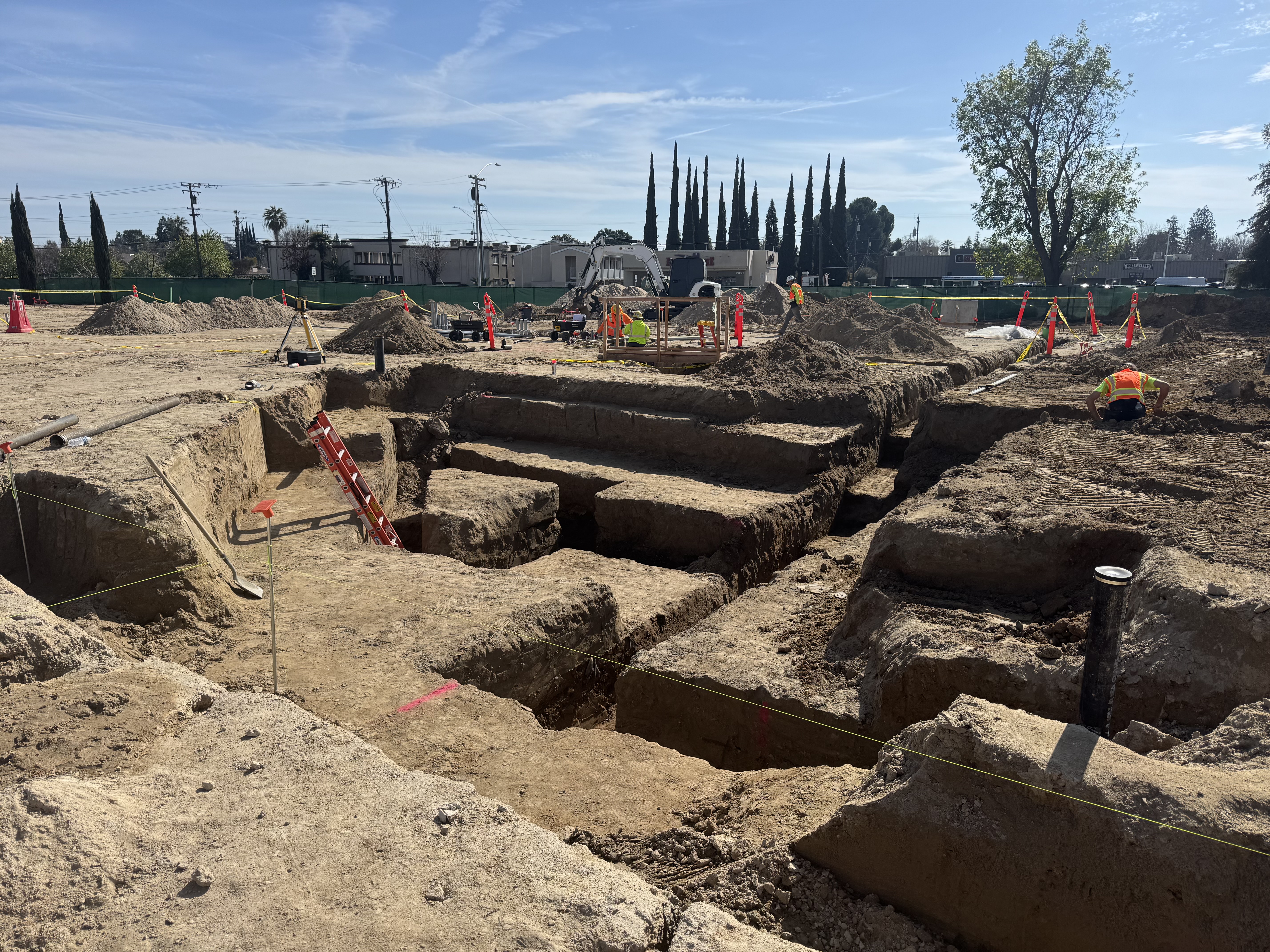 Wide view of commercial excavation site with multiple trenches and crew in Northern California