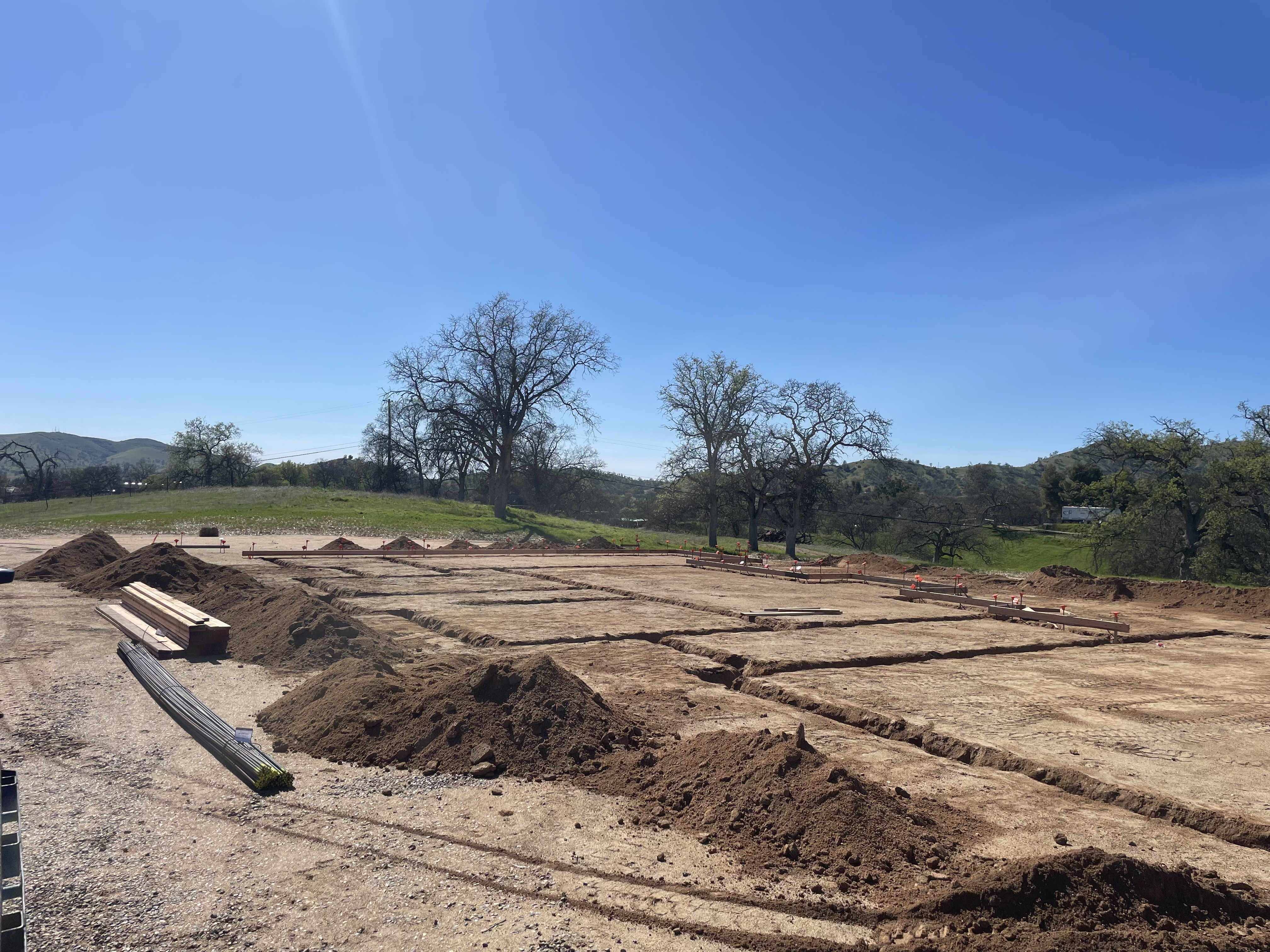 Commercial foundation trench layout across open field, Northern California oaks in background