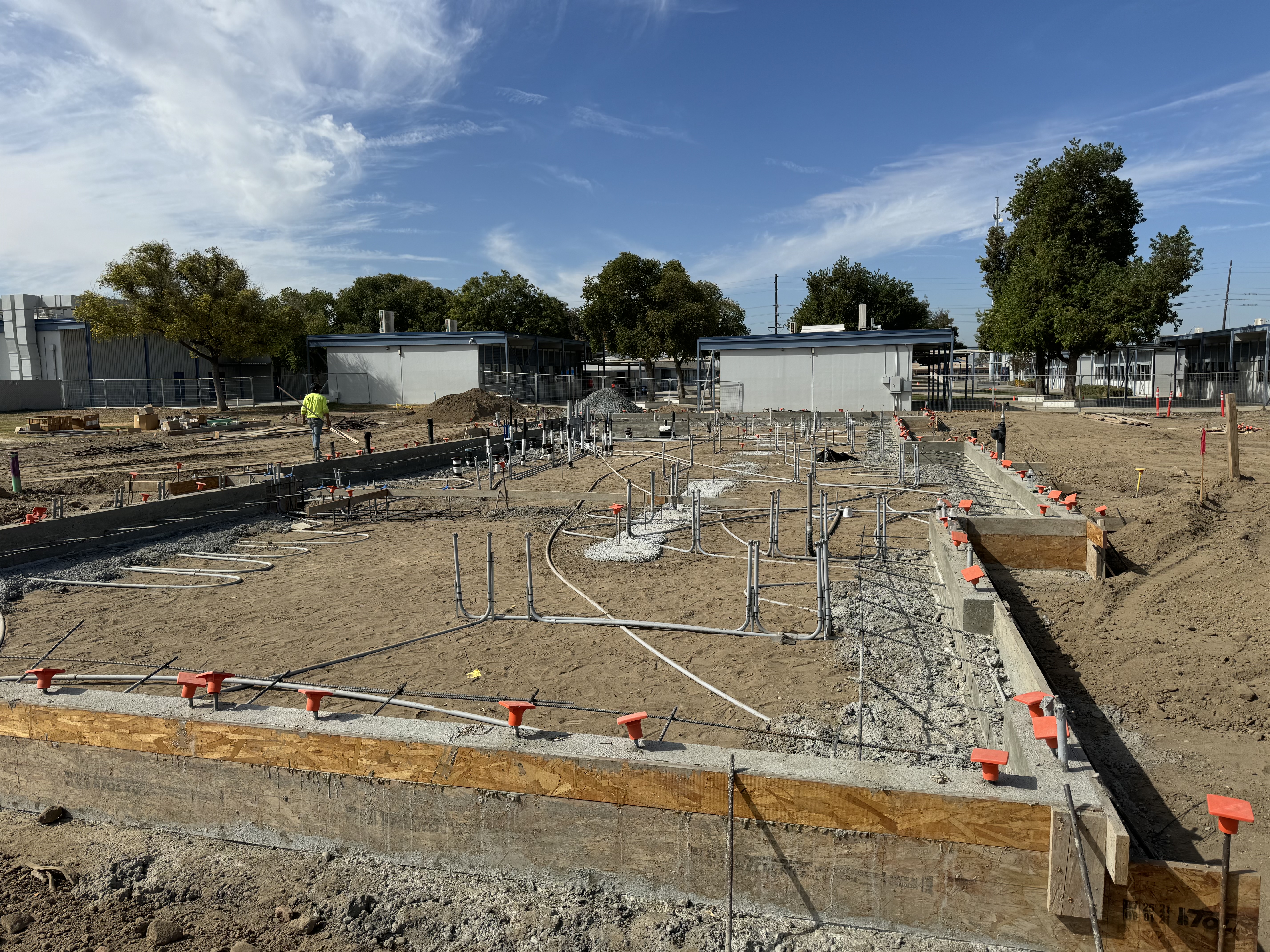 Commercial foundation prep with post-tension cables and formwork layout on construction site