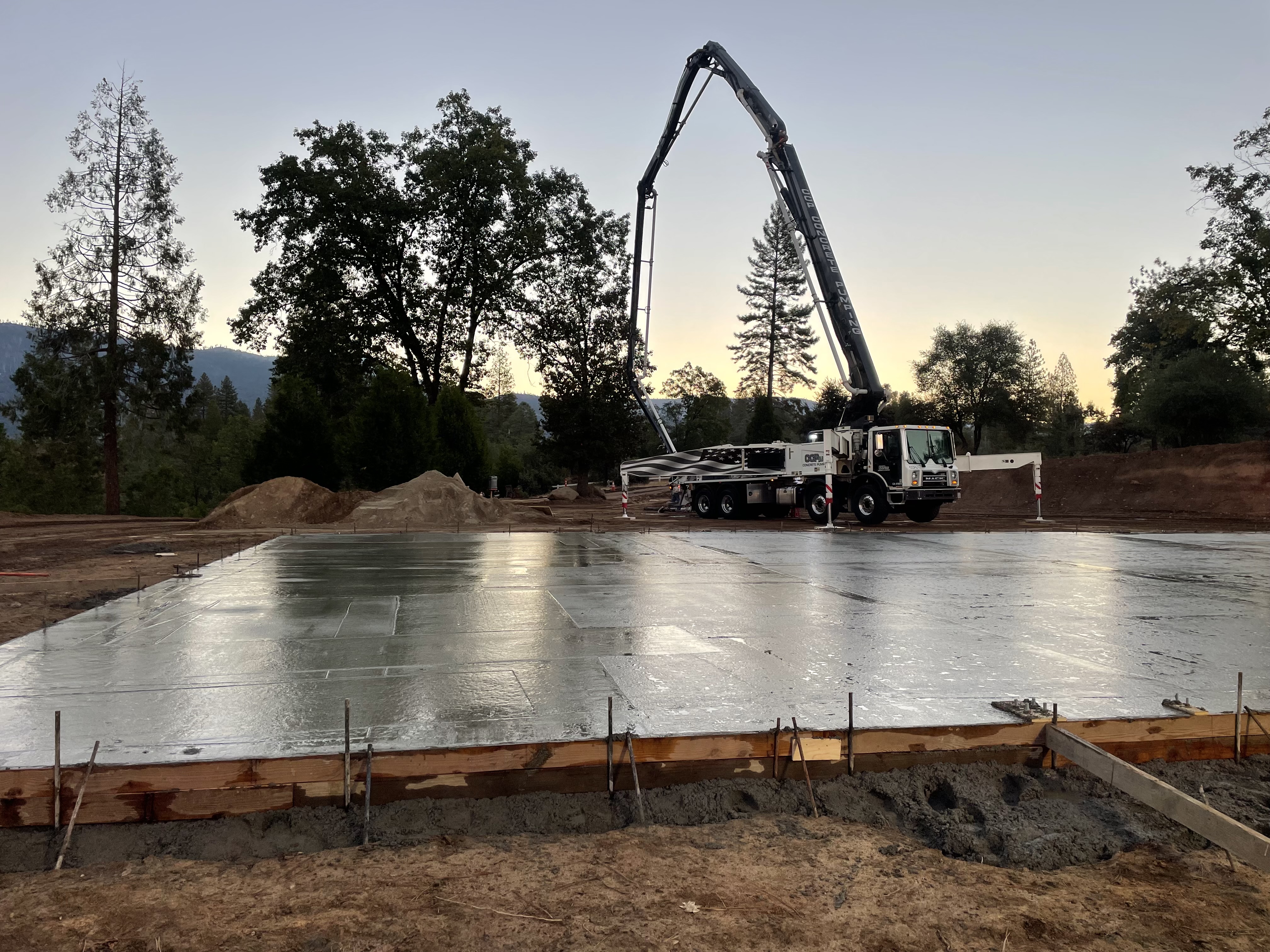 Concrete pump truck placing large commercial slab at sunrise on Northern California job site