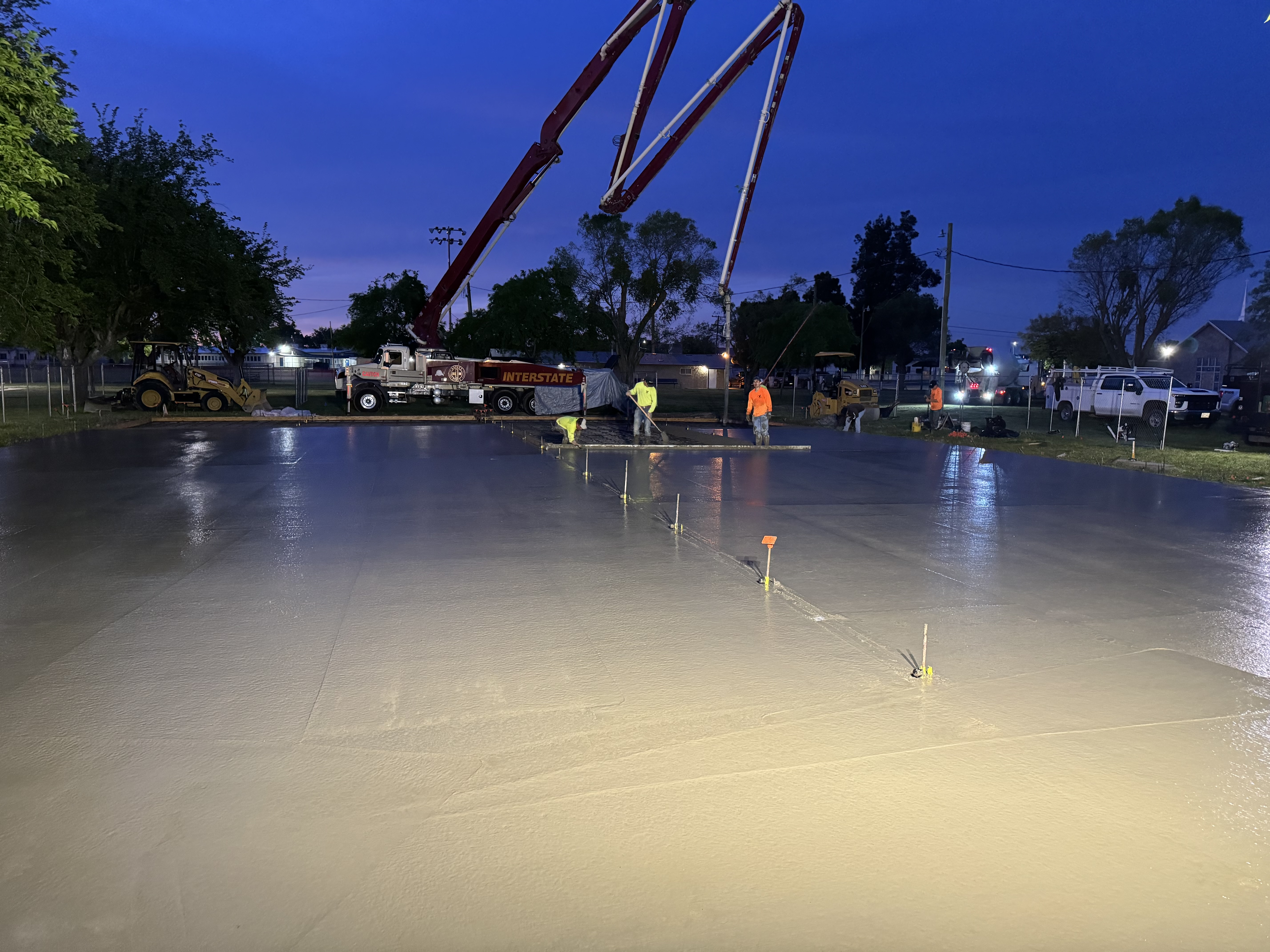 Concrete slab pour at dusk with pump truck and crew at commercial project in Northern California