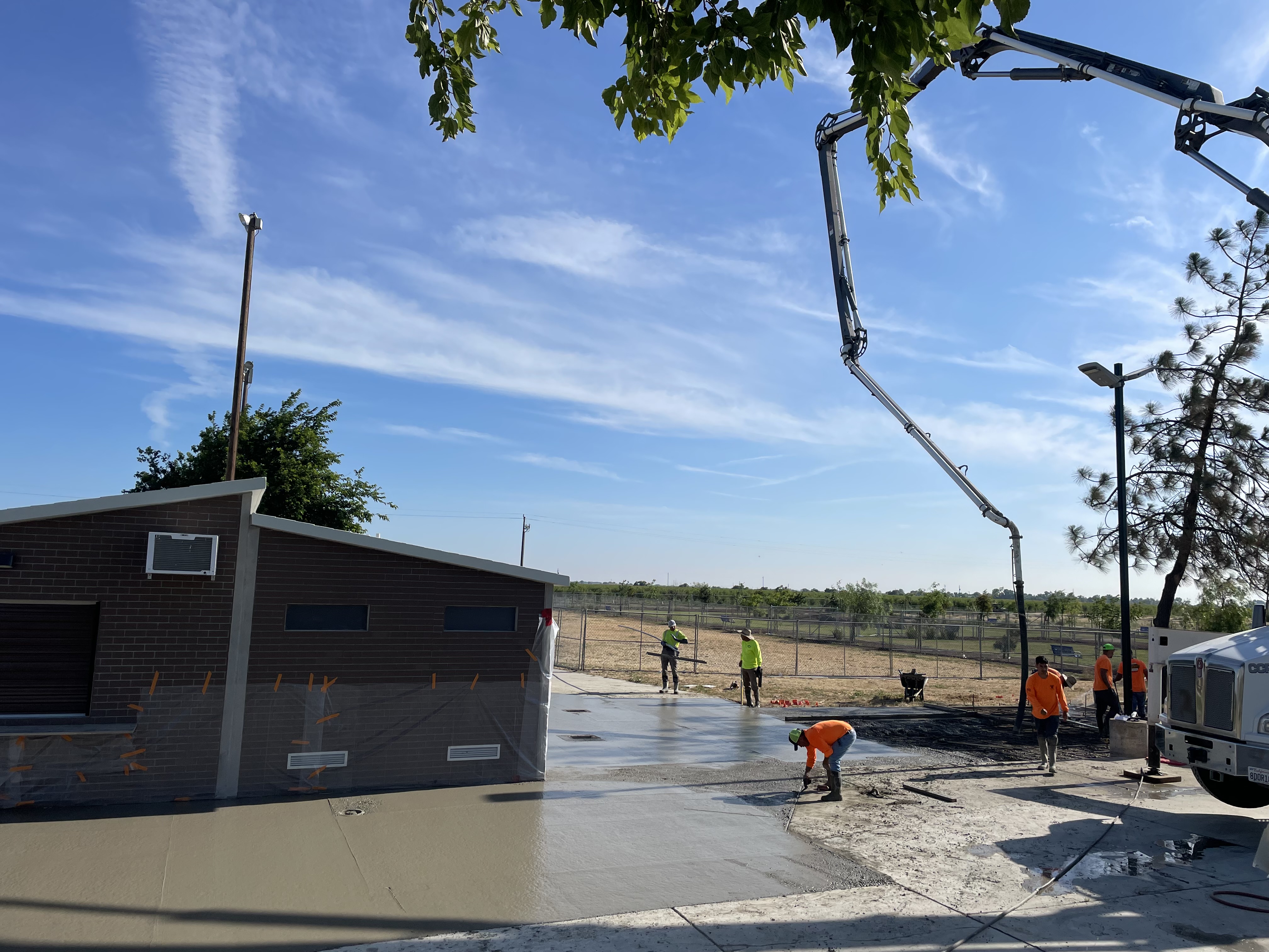 Crew and pump truck placing concrete slab on commercial construction project in Northern California