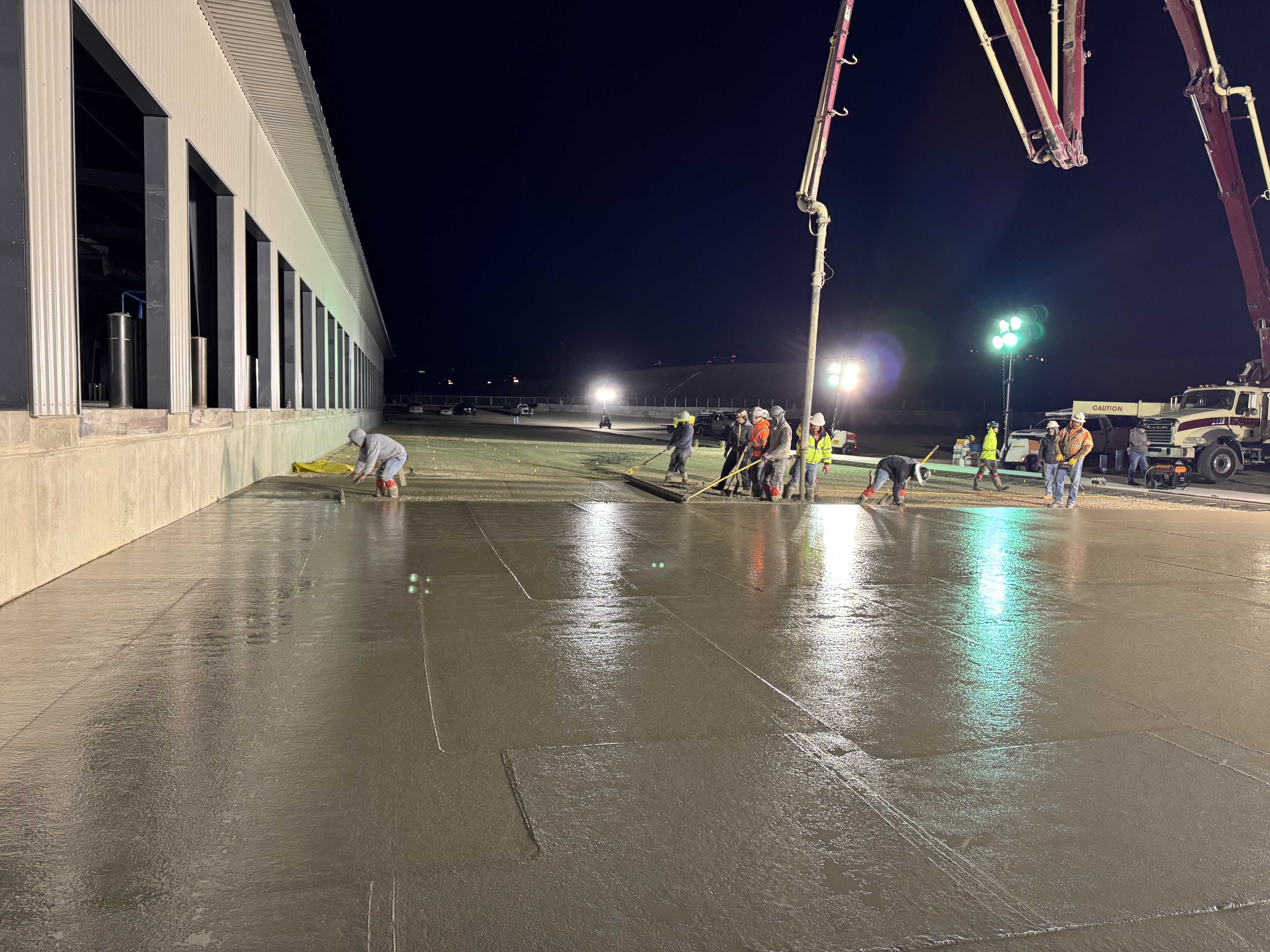 Liaison Concrete Construction crew placing commercial concrete slab at night with pump truck on large warehouse project