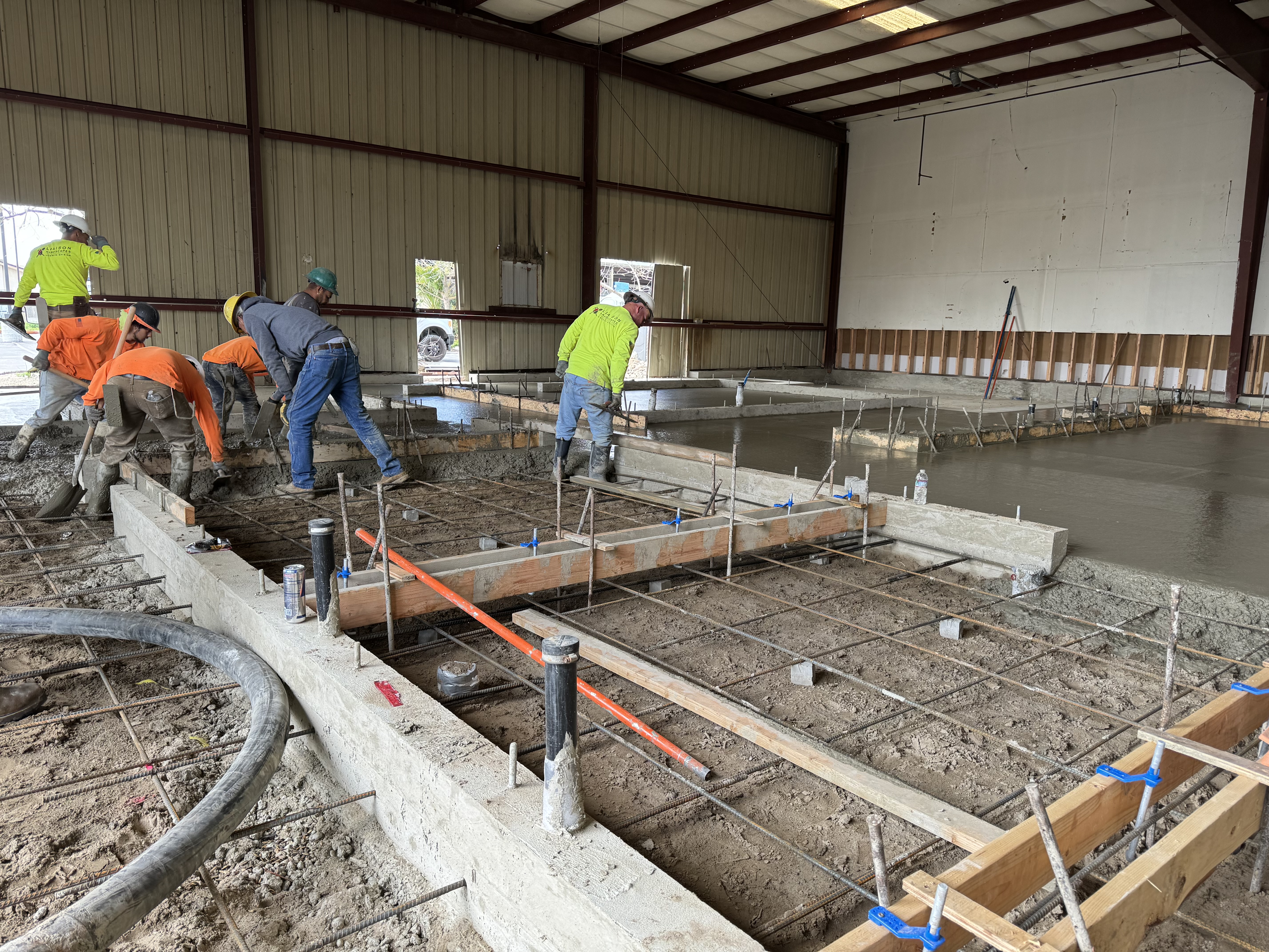 Crew pouring and finishing concrete slab inside commercial warehouse building