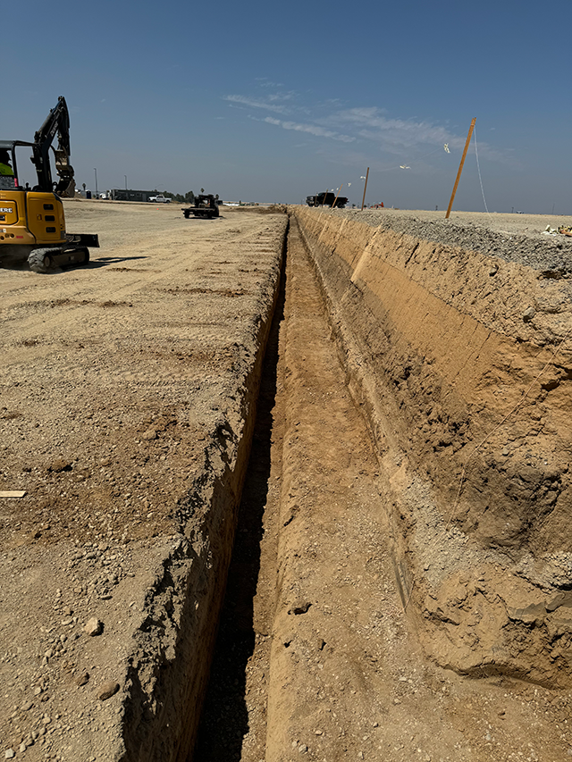 GPS-guided excavator grading a commercial building pad for a warehouse project