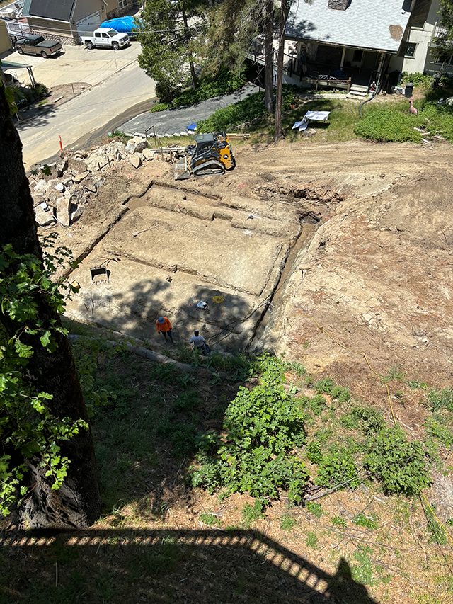 Large excavator performing site clearing and earthwork on a commercial development